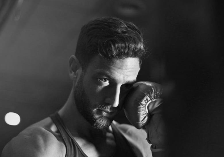 A black and white image of a man holding a boxing glove to his head