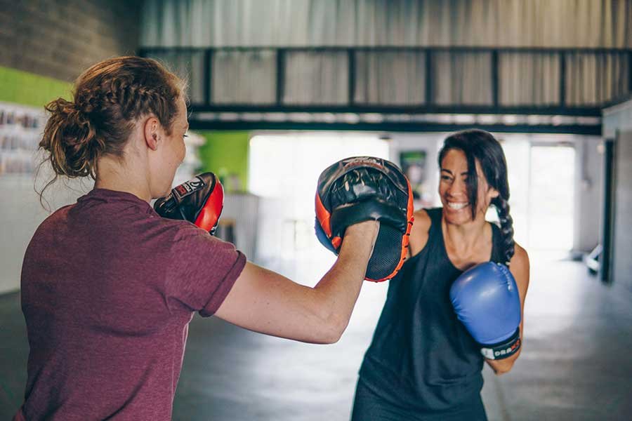 A smiling woman punching a practice pad