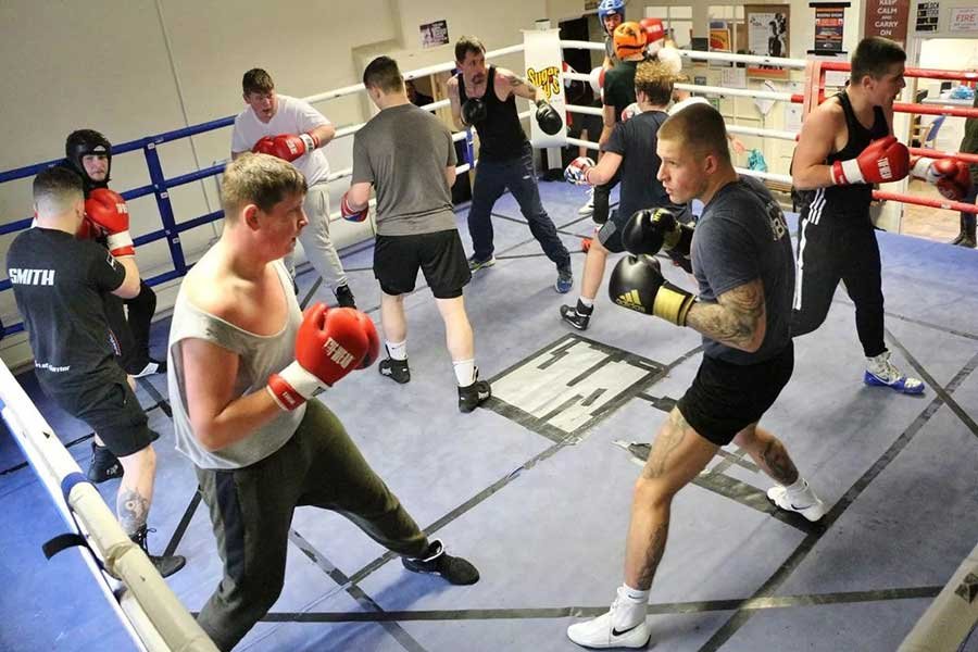 People standing in a boxing ring, practicing