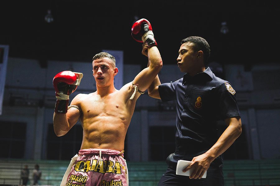 A man raising his fist in victory after a boxing match