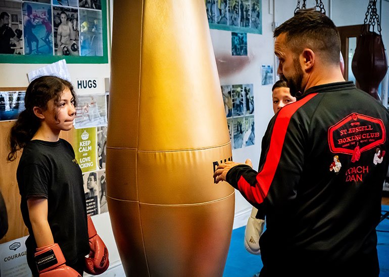 Coach Dan training a young lady next to a punching bag